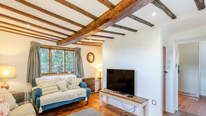 A cozy room with a bed, a TV, and a window with curtains. - 2 bedroom accommodation in Much Hadham (Much Hadham)