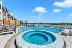 A swimming pool with a hot tub, lounge chairs, and a view of a lake. - Lone Star Landing | Concierge Services (Kingsland)