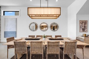 A dining area with a long table, wicker chairs, and a central light fixture. - Lone Star Landing | Concierge Services (Kingsland)