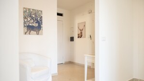 A white interior with a white chair, a small table, and two deer paintings on the walls. - Roma per te - One Bedroom Apartment, Sleeps 4 (Rome)
