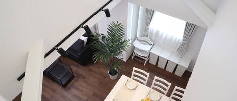 A dining area with a table set for four, a potted plant, and a staircase leading to another level.