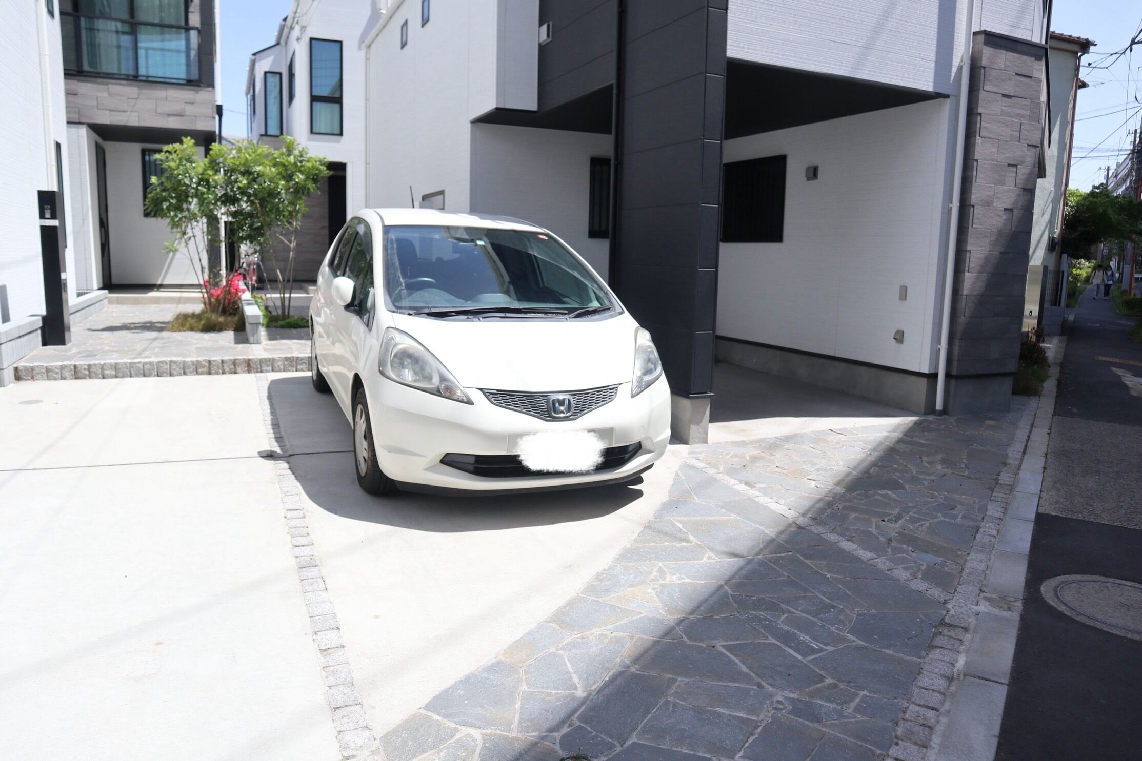 A white car parked in a driveway with a modern house in the background.