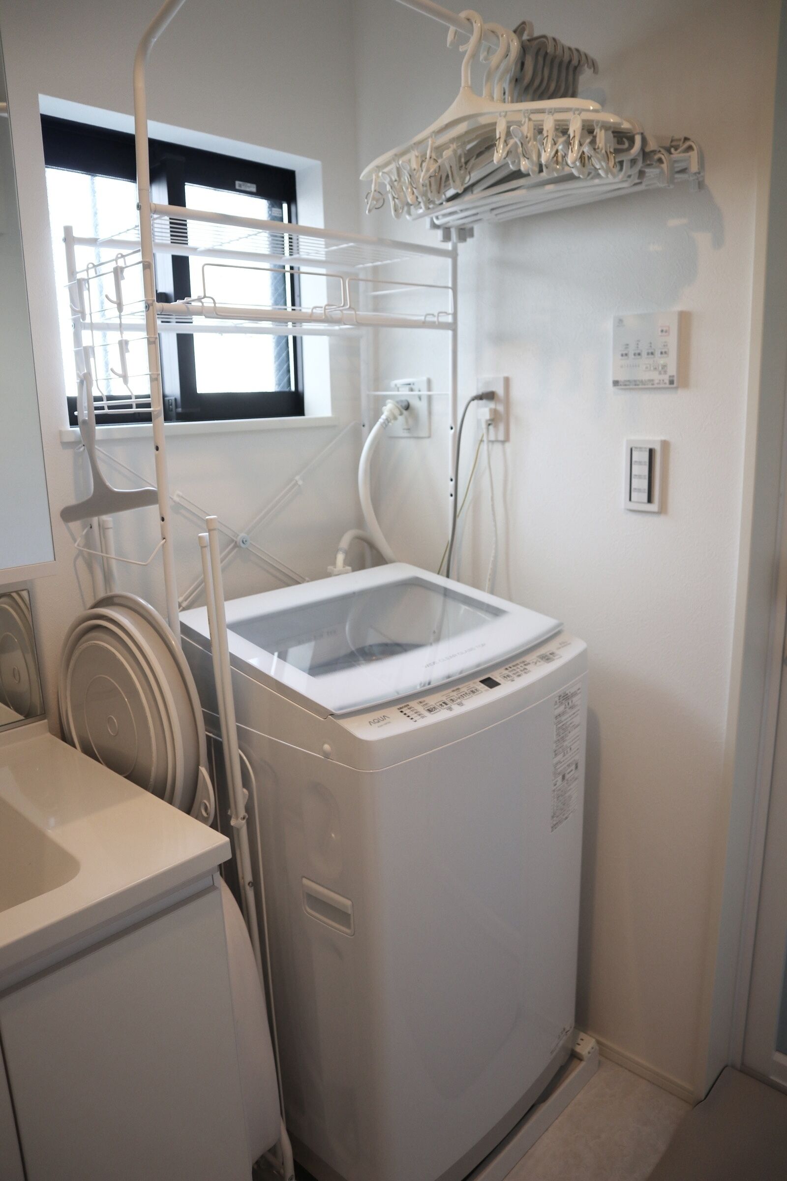 Une buanderie équipée d’un lave-linge, d’un étendoir et d’une fenêtre.