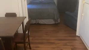 Une chambre comprenant un lit, une télévision, une commode et une table à manger avec des chaises.