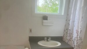 Une petite salle de bain avec des toilettes, un lavabo et une fenêtre.