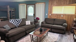 A cozy living room with two sofas, a coffee table, and a bunk bed in the background. - Cozy Cabin- Close to all up North activities! Cabin in Irons. (Irons)