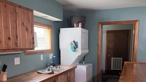 A compact kitchen with wooden cabinets, a white refrigerator, and a sink. - Cozy Cabin- Close to all up North activities! Cabin in Irons. (Irons)