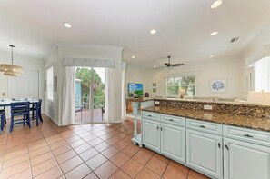 A kitchen with white cabinetry, a granite countertop, and a ceiling fan.