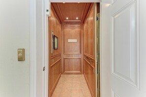 A hallway with wooden paneling, a 'RELAX' sign, a security keypad, and a door with a handle.