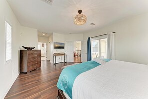 A bedroom with a bed, dresser, and a view of the balcony.