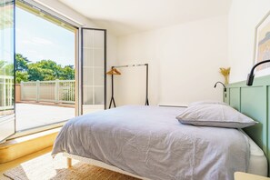 Relax in a serene space with a large bed and sliding glass door leading to a balcony with a view.