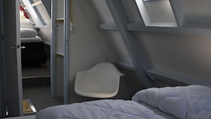 Une pièce avec un lit, une chaise et une lucarne.