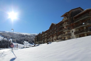 A multi-story wooden building with balconies, likely a hotel, set against a snowy mountain backdrop. - 200m from resort center, 3rd floor, view mountain, tv, ski locker, 32m², Superdévoluy (Le Dévoluy)