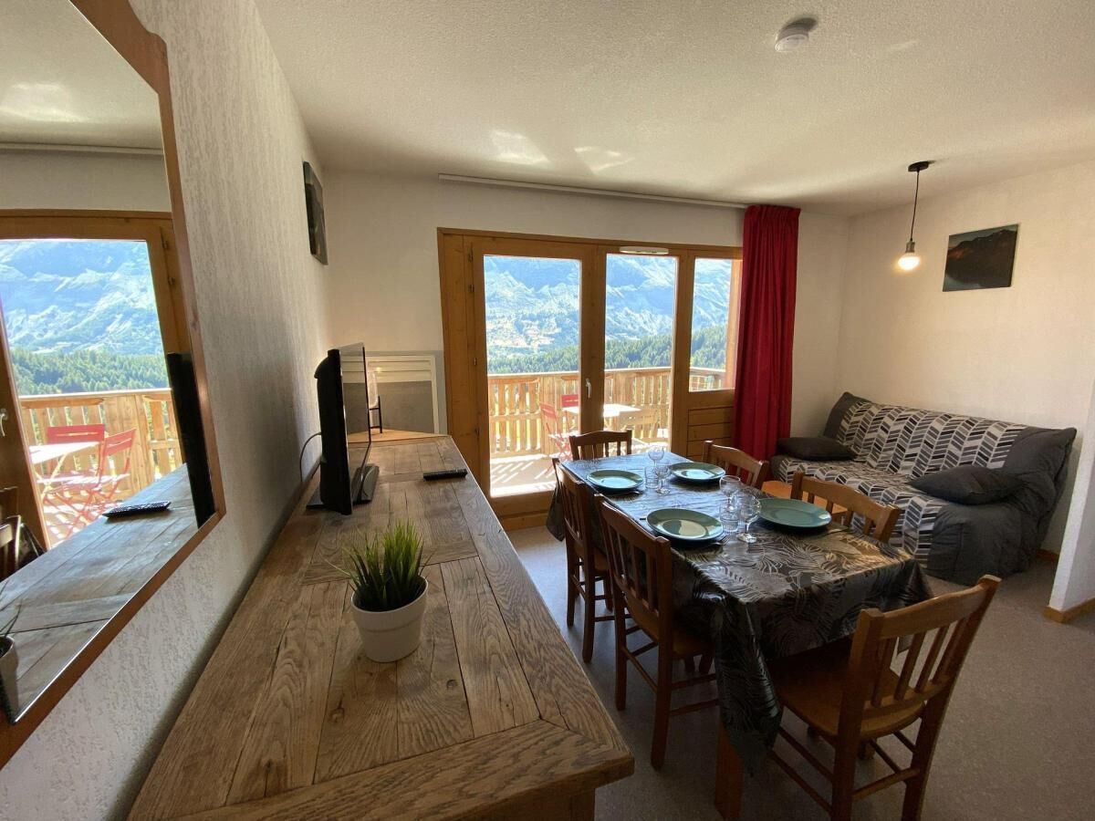 Ein Essbereich mit einem Holztisch, Stühlen und Blick durch große Fenster.