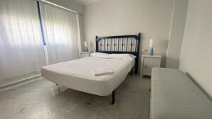 A bedroom with a bed, bedside tables, a bench, and a window with curtains. - Canal Salinas 1º ático Solo Familias! (Xeraco Playa)