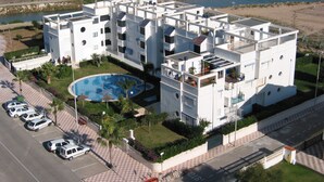 A multi-story hotel with a swimming pool, parking lot, and a beach view. - Canal Salinas 1º ático Solo Familias! (Xeraco Playa)