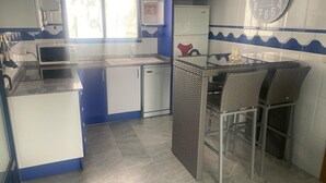 A kitchen with a microwave, refrigerator, and a clock on the wall. - Canal Salinas 1º ático Solo Familias! (Xeraco Playa)