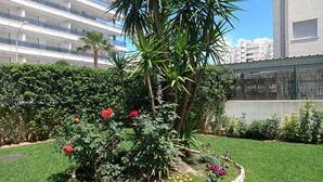A landscaped garden with a palm tree, red and pink flowers, and a stone border.
