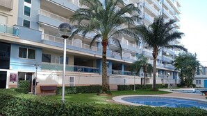 A multi-story hotel with balconies, a swimming pool, and well-maintained greenery.