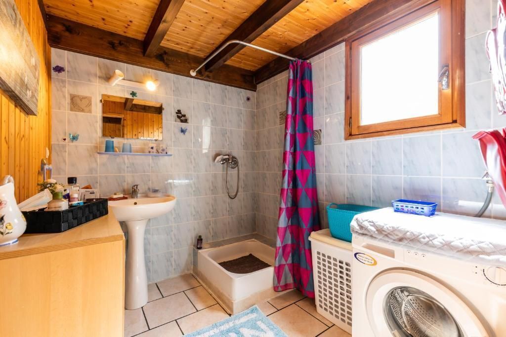 Un baño con lavamanos, ducha y lavadora.