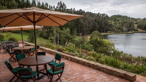 Un patio con mesas al aire libre y vista a un lago.