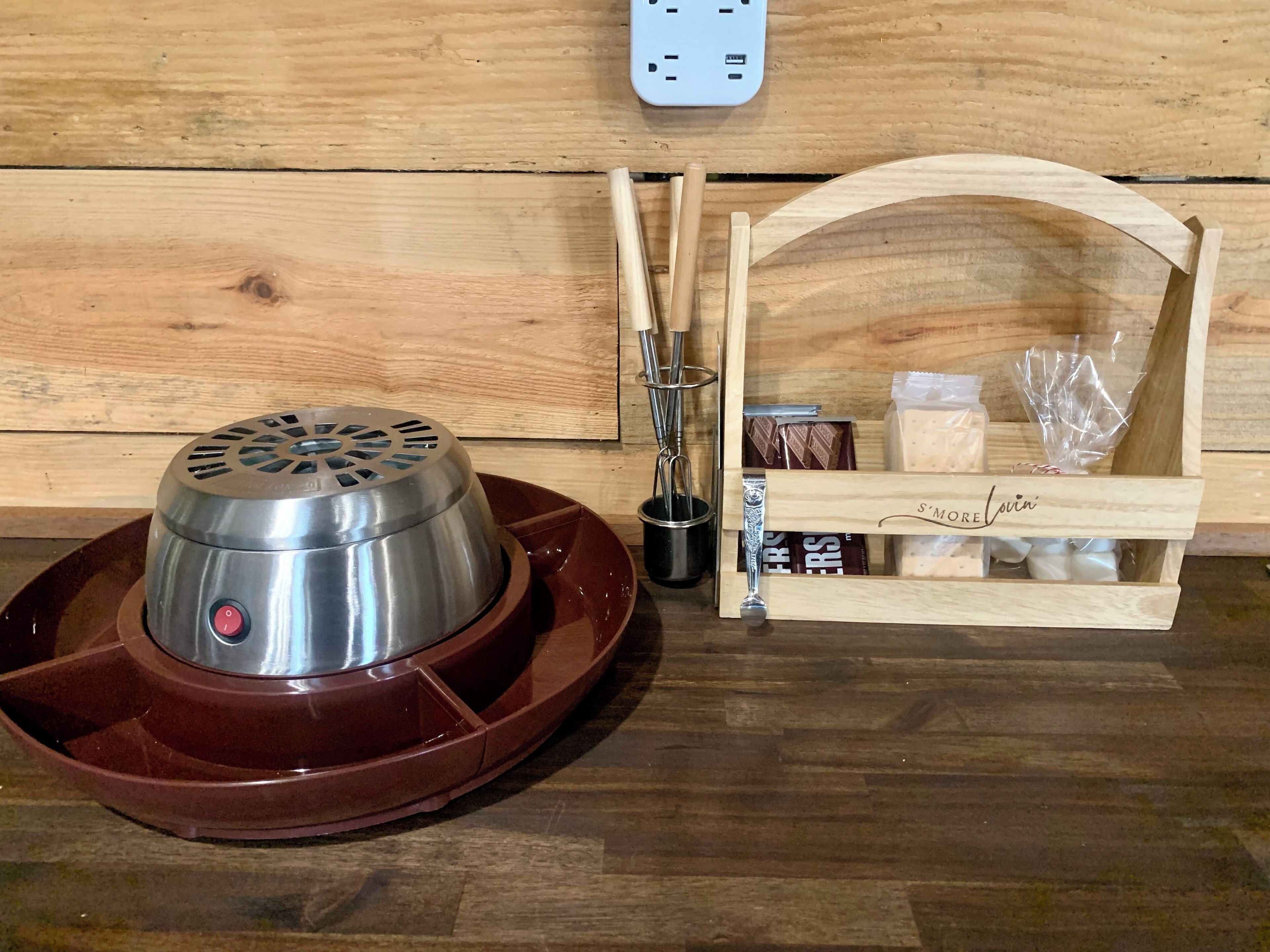 A portable electric heater with a control panel, a wooden tray, a set of chopsticks, a small container, and a wooden box with a label.