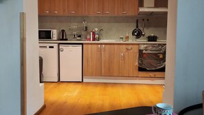 Una cocina compacta con armarios de madera, microondas, hervidor y lavavajillas.