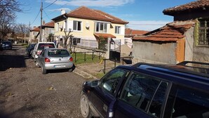Una calle residencial con casas, coches estacionados y cielo despejado.