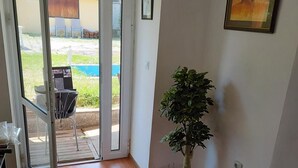 Una habitación con puerta corrediza de vidrio que da a un área exterior, una planta en maceta y un cuadro en la pared.