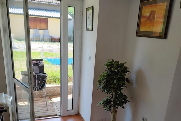 Una habitación con puerta corrediza de vidrio que da a un área exterior, una planta en maceta y un cuadro en la pared.