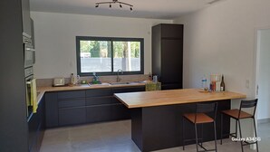 Una cocina moderna con una isla central, muebles oscuros y un ventanal que aporta luz natural.