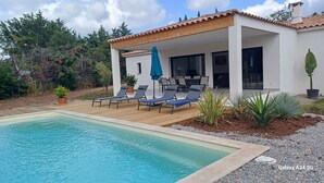Una casa moderna con piscina, mobiliario exterior y zona de patio.