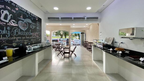 A clean, modern cafe with a chalkboard wall displaying messages and a seating area with tables and chairs. - Pousada Mar Suites (Ubatuba)