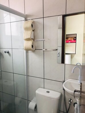 A bathroom with a toilet, sink, and a mirror. - Pousada Mar Suites (Ubatuba)