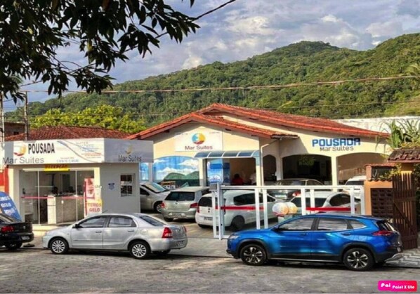 A hotel with a red roof and multiple cars parked in front. - Pousada Mar Suites (Ubatuba)