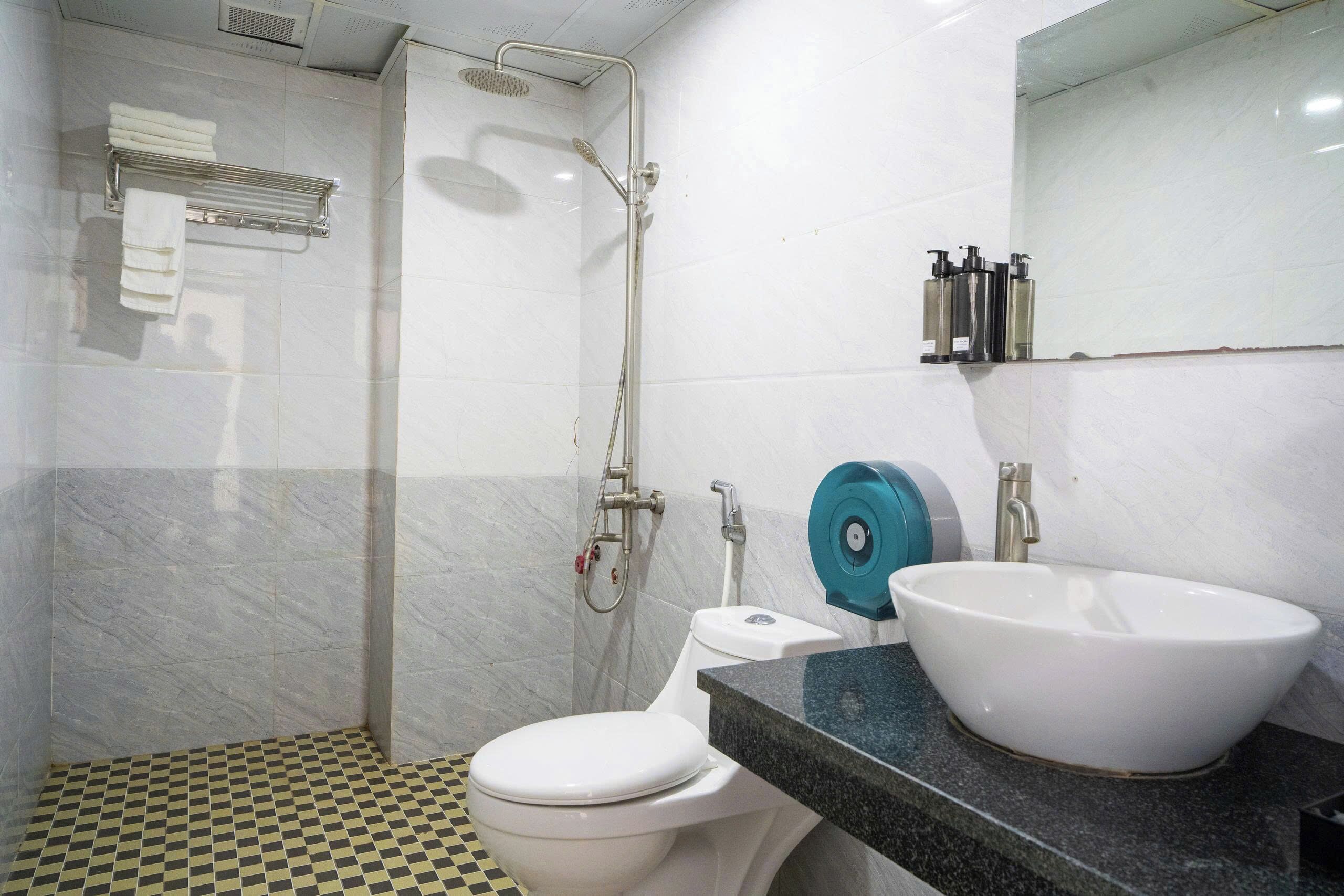 A bathroom with a toilet, sink, shower, and tiled floor.