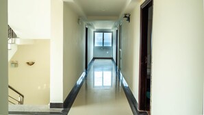 Un pasillo de hotel con una señal de salida visible, una escalera a la izquierda y una puerta a la derecha.