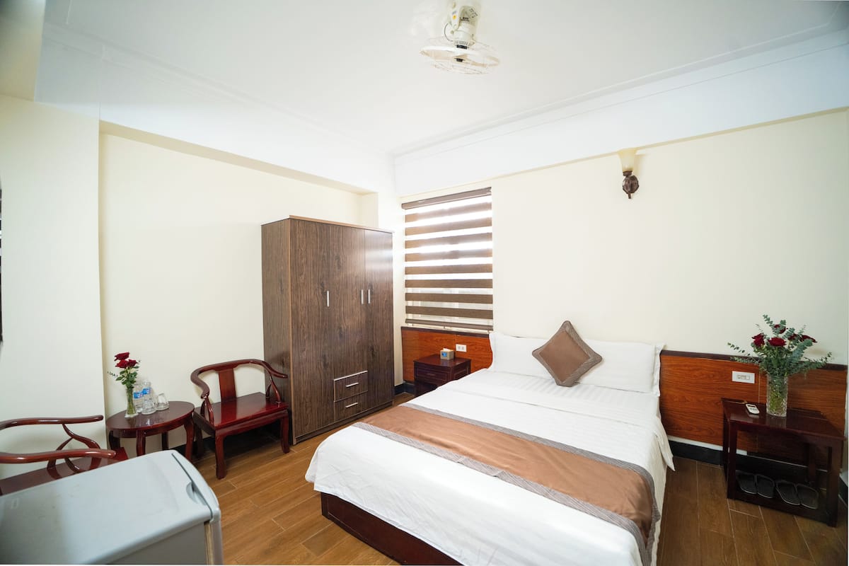 A hotel room with a bed, a wardrobe, a desk, and a chair.