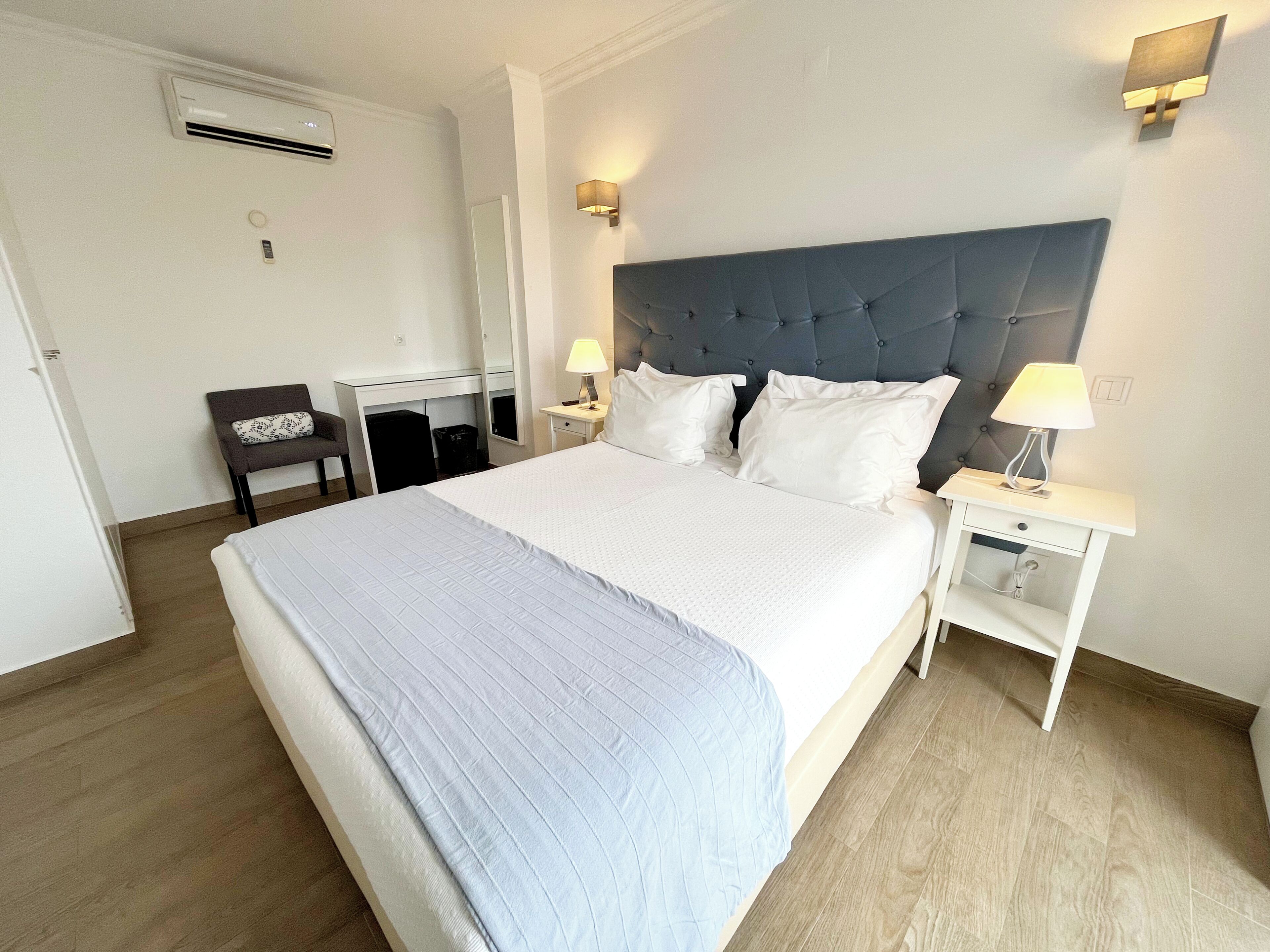 A hotel room with a large bed, a desk, and a chair.