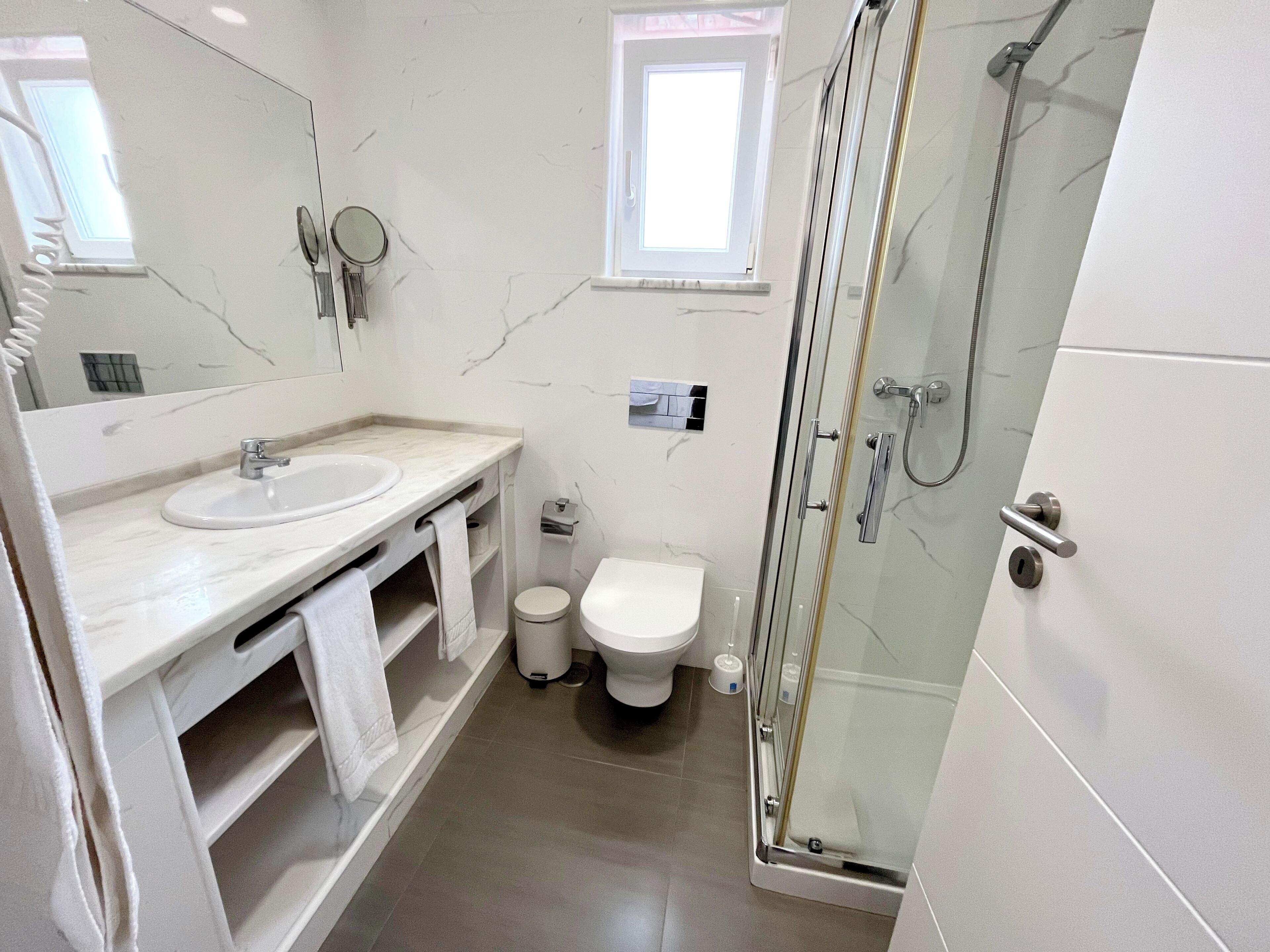 A modern bathroom with a glass-enclosed shower, a sink, and a toilet.
