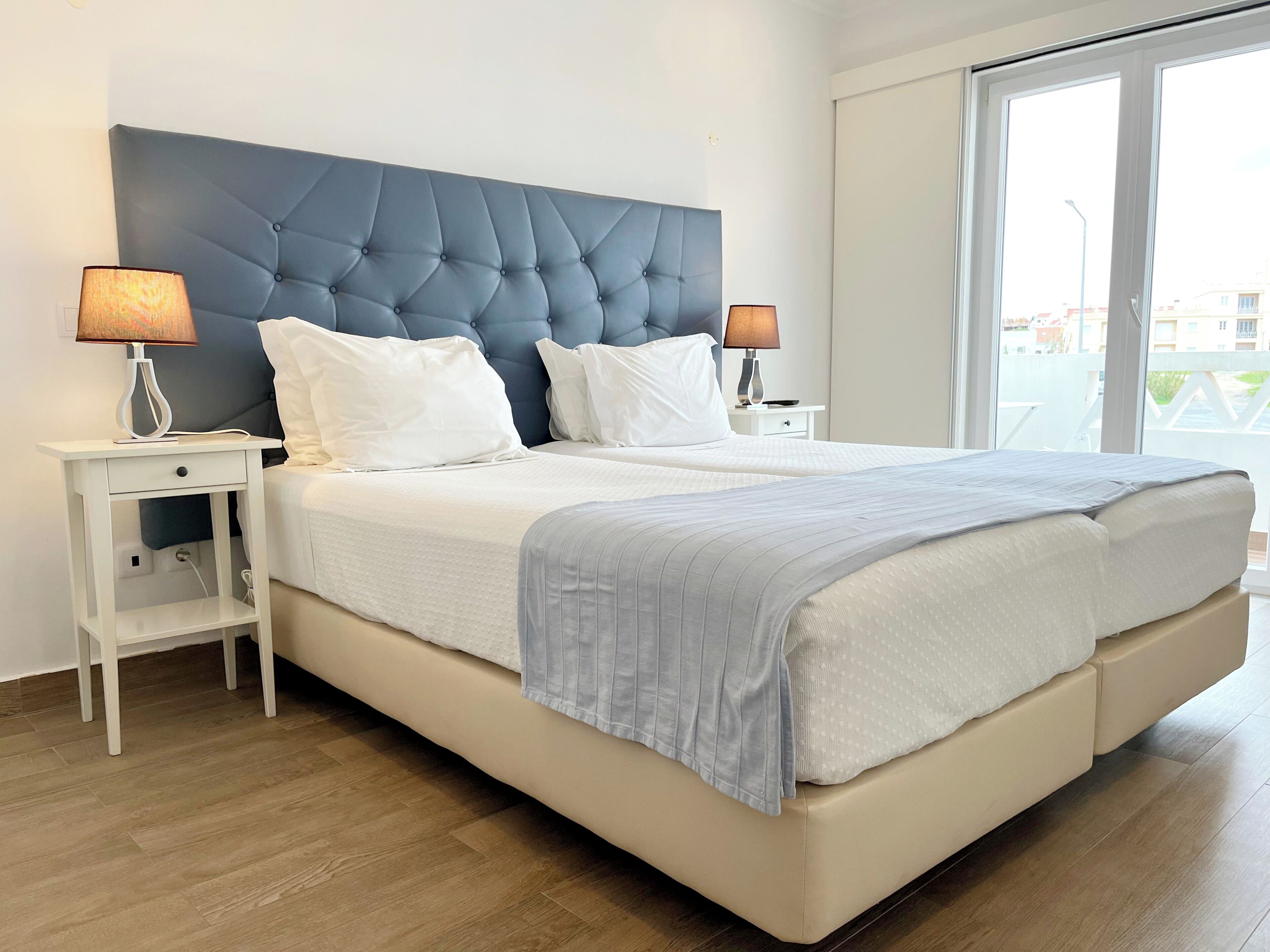 A bedroom with a large bed, two bedside tables, and a window with a view.