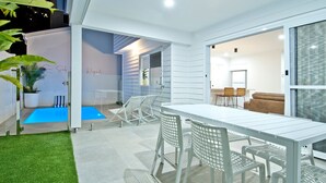 A modern outdoor patio with a pool, white furniture, and a glass door leading to an interior space. - Freedom Beach Homes Unit 199B Brand New in Rainbow Bay with private plunge pool and Wi-Fi Inc. (Coolangatta)