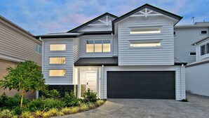 A two-story house with a garage, a front door, and a small garden with various plants. - Freedom Beach Homes Unit 199B Brand New in Rainbow Bay with private plunge pool and Wi-Fi Inc. (Coolangatta)