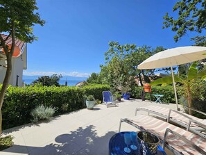 A patio with outdoor furniture, a large umbrella, and a view of the sea. - Holiday apartment with terrace and sea view (Njivice)