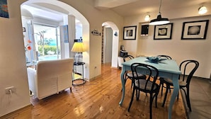 A dining area with a blue table and black chairs, a yellow lamp, and framed pictures on the wall. - Holiday apartment with terrace and sea view (Njivice)