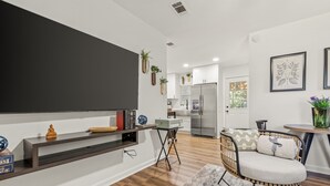 A modern kitchen with a built-in refrigerator, a dining area with a round table and chairs, and a living area with a sofa and a coffee table.