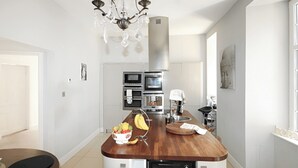 A modern kitchen with a central island, built-in appliances, and a chandelier.