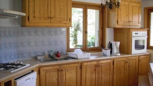 Una cocina con armarios de madera, estufa a gas, lavavajillas y cafetera.