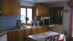 Una cocina con armarios de madera, una mesa de comedor con sillas y un ventanal.