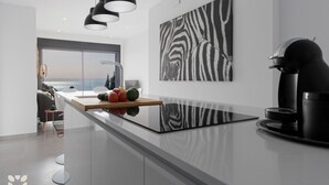 Une cuisine moderne dotée d’un grand îlot central, de luminaires suspendus noirs et d’une œuvre d’art à motifs zébrés accrochée au mur.